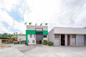 een wit en groen gebouw met een parkeerplaats bij Ayenda Panamericana in Manizales