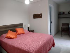 - une chambre dotée d'un lit avec deux oreillers orange dans l'établissement Casas Adilio Florianopolis-norte, à Florianópolis