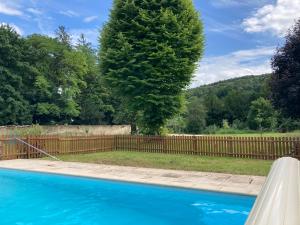 uma cerca e uma piscina azul com uma árvore em Villa Fémina em Savigny-lès-Beaune
