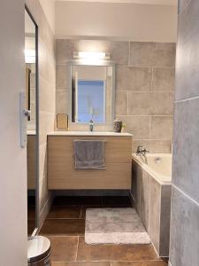 La salle de bains est pourvue d'un lavabo, d'une baignoire et d'un miroir. dans l'établissement Sea View & More…, à Saint-Denis