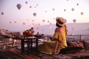 a woman sitting on a balcony looking at hot air balloons at Sultan Cave Suites in Göreme