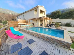 a swimming pool with chairs and a house at Appartement Piovanacce - T3 avec pisicne privée 10min de Saint-Florent in Barbaggio