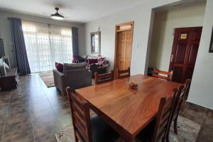 a dining room and living room with a wooden table at Charming 2-Bed Apartment in Kigo in Kampala