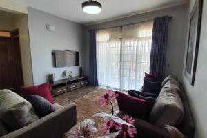 a living room with two couches and a large window at Charming 2-Bed Apartment in Kigo in Kampala