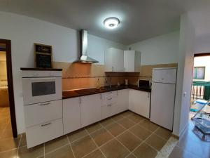 a kitchen with white cabinets and a stove top oven at Casa Cactus in Pájara