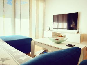 Apartamento Con Piscina Lloret de Mar في يوريت دي مار: غرفة معيشة مع تلفزيون ووعاء على طاولة