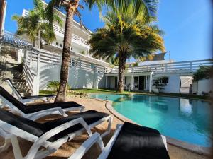 einen Pool mit Chaiselongues neben einem Gebäude in der Unterkunft PENTHOUSE Jan Thiel Curacao in Willemstad