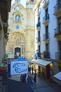 een gebouw met een klokkentoren en een bord voor bij Go Donosti Santa Maria in San Sebastian