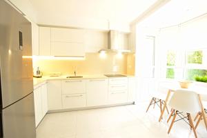 cocina con armarios blancos, mesa y sillas en Go Donosti Villa Berio, en San Sebastián