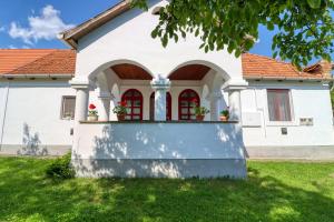 biały dom z czerwonymi oknami w obiekcie Napfény Vendégház w mieście Bükkszék