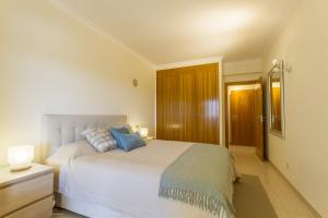 Un dormitorio con una gran cama blanca con almohadas azules. en Millennium Plaza, en Vilamoura 12 fotos más