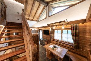 a room with a table and stairs in a cabin at Chalet Catinaccio Rosengarten 56 in Pozza di Fassa