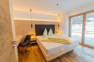 a bedroom with a bed and a desk and a chair at Ganovhof - Deluxe Chalet in San Valentino alla Muta