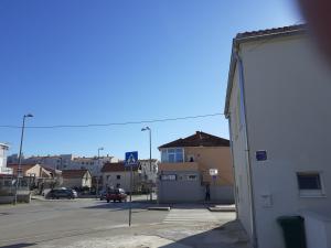 ulica miejska z białym budynkiem i parkingiem w obiekcie Studio apartman LORENA w mieście Zadar