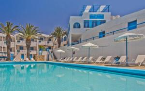 a swimming pool with chairs and umbrellas next to a building at Bluu Bahari Hotel in Karpathos Town
