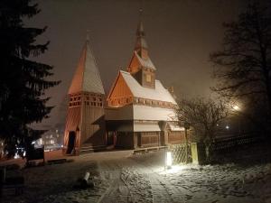 uma grande igreja com um edifício coberto de neve à noite em Ferienwohnung Isabell em Hahnenklee-Bockswiese