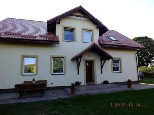 une maison blanche avec un banc dans la cour dans l'établissement Agroturystyka Wielkie Leźno, à Wielkie Leżno