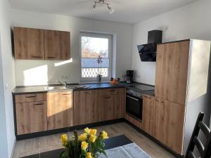 eine Küche mit Holzschränken und Spüle und einem Fenster in der Unterkunft Ferienwohnung Am Südhang in Göhren