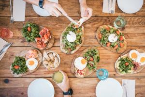 a group of people eating food on a wooden table at MUTE Hostel Porto Covo in Porto Covo +35 photos