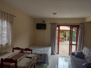 a bedroom with a bed and a couch and a tv at Chalé Família in Companhia