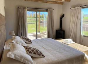 a bedroom with a large bed with a large window at La Carrera Villas, Atamisque. Tupungato, Mendoza. in Ciudad Lujan de Cuyo