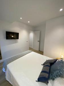 a bedroom with a white bed with a tv on the wall at LINEROS SUITE in Córdoba