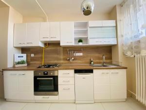 a kitchen with white cabinets and a sink at Zrinyi Central Apartman with free parking in Nyíregyháza