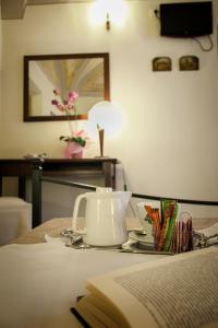 a table with a tea kettle and a book on it at Camere Del Re in Tarquinia