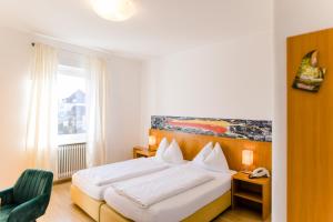 a bedroom with a white bed and a green chair at Hotel Wirtshaus Römerhof in Leibnitz +32 photos