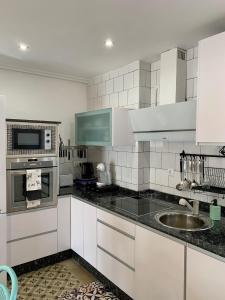 a kitchen with white cabinets and a sink at Alojamiento estilo Boho con mucho encanto in Ponferrada