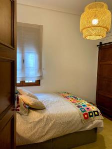 um quarto com uma cama, uma janela e um lustre em Alojamiento estilo Boho con mucho encanto em Ponferrada