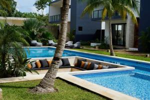 a swimming pool with palm trees next to a house at Kaanal Tulum in Tulum
