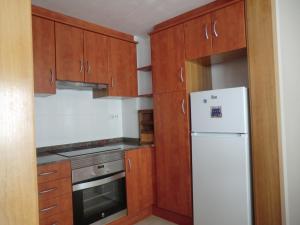 een keuken met houten kasten en een witte koelkast bij Flor de Lis in Benasal