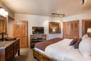 een slaapkamer met een bed, een wastafel en een televisie bij Stunning Zephyr Mountain Lodge Condo Overlooking The Village Plaza condo in Winter Park