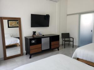1 dormitorio con TV y tocador con espejo en Hotel CaLu 21 en La Laguna, Santa María del Oro, en Santa María del Oro