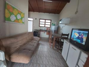een woonkamer met een bank en een tv en een keuken bij 0006.03 - Maranduba - Chalé - 1 Dorm - 5 Pess - 3 Quadras Do Mar - Piscina Coletiva - WIFI in Ubatuba