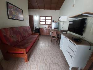 een woonkamer met een bank en een flatscreen-tv bij 0006.02 - Maranduba - Chalé - 1 Dorm - 5 Pess - 3 Quadras Do Mar - Piscina Coletiva - WIFI in Ubatuba