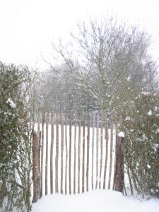 une clôture recouverte de neige avec des arbres en arrière-plan dans l'établissement Gîte ardennais Rogery - Yá-át-ééh Naşbaş, à Gouvy