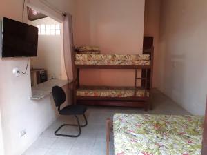 um quarto com duas camas e uma cadeira e uma televisão em 0001.11 - Maranduba - Kitnet Térreo - 4 Pessoas - 2 Quadras Do Mar - Piscina - Wi-Fi - Ar Condicionado em Ubatuba