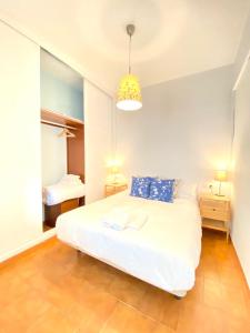 een slaapkamer met een groot wit bed met blauwe kussens bij Comfortable studio old town, parking optional in Sevilla