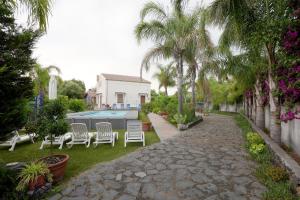 a yard with chairs and a swimming pool with palm trees at Casa delle foglie in San Giovanni la Punta