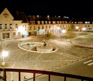 a building with a fountain in a courtyard at night at Le Soleil D'or in Vimoutiers