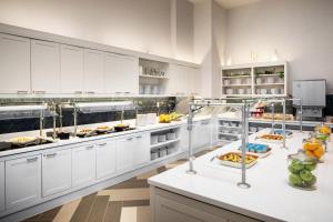 ニューヨークにあるHyatt Place New York Chelseaの白いキャビネットとカウンターの上に食べ物が置かれた広いキッチン