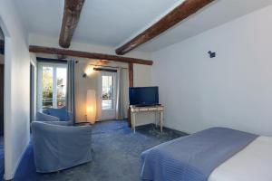 - une chambre avec un lit et une télévision dans l'établissement Le Cheval Blanc, à La Bastide-des-Jourdans