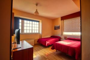 a hotel room with two beds and a television at Pension Escalinata in Sarria