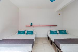three beds in a room with blue pillows at Ayenda Oasis Airport in Mexico City