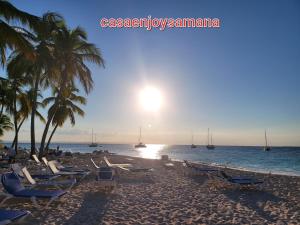 a beach with chairs and palm trees and the ocean at casaenjoysamana in Los Naranjos