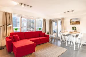 a living room with a red couch and a table at Las Dunas - 30m van het strand in Ostend