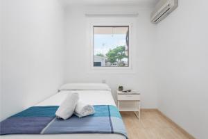 a white bedroom with a bed and a window at Casa Hawaii in Port d'Alcudia