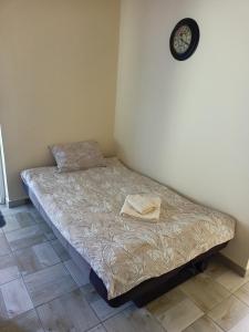 un piccolo letto in una stanza con un orologio a muro di Apartman FiVa2 a Pačir
